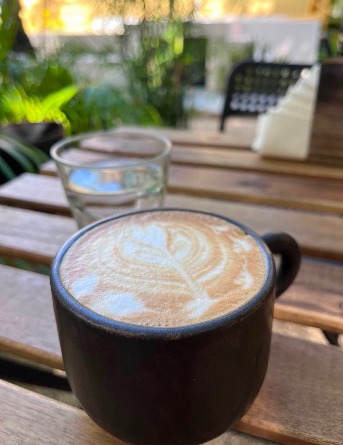 Taza de café con arte latte servida en Migrante Café